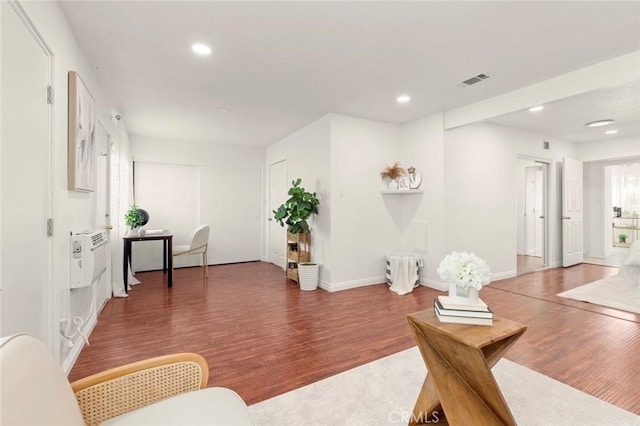 living room with a wall mounted air conditioner and dark hardwood / wood-style floors