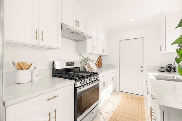 kitchen featuring light tile patterned floors, sink, light stone countertops, white cabinets, and gas range