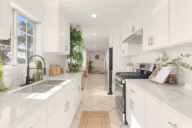 kitchen featuring appliances with stainless steel finishes, white cabinetry, sink, light tile patterned floors, and light stone countertops