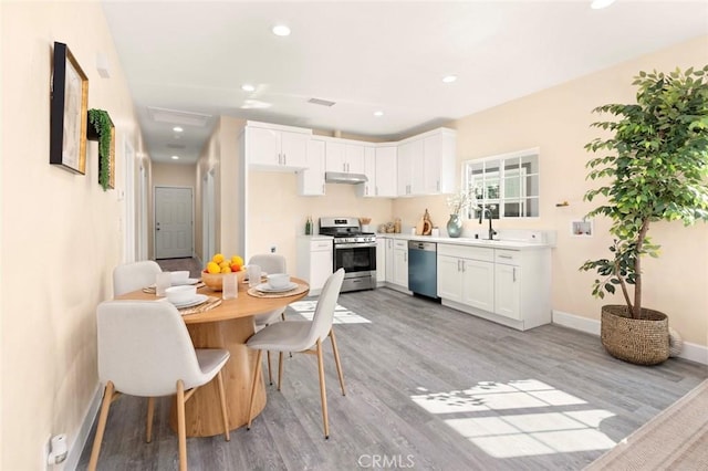 kitchen with appliances with stainless steel finishes, sink, light wood-type flooring, and white cabinets