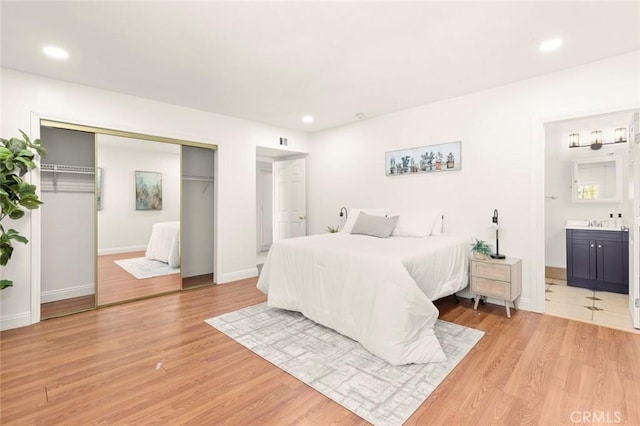 bedroom with light hardwood / wood-style floors, a closet, and ensuite bathroom