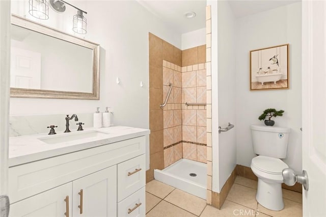 bathroom featuring tiled shower, vanity, toilet, and tile patterned flooring