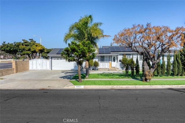 view of front of house featuring a garage, a front yard, and solar panels