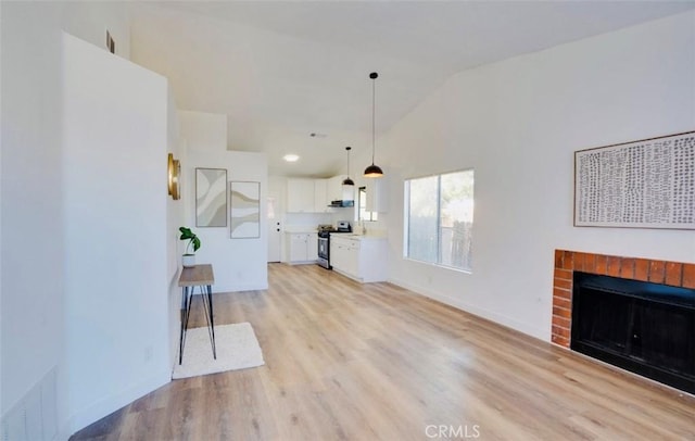 unfurnished living room featuring a brick fireplace, high vaulted ceiling, and light wood-type flooring