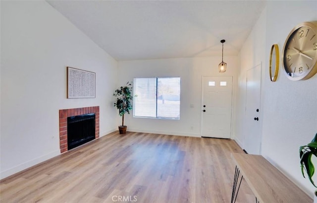 entrance foyer featuring lofted ceiling, a fireplace, and light hardwood / wood-style floors