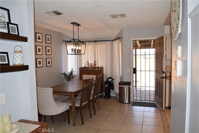 tiled dining area with a chandelier and a textured ceiling