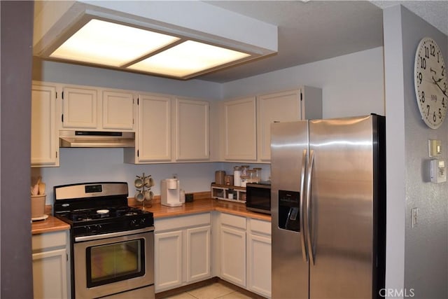 kitchen with white cabinetry, stainless steel appliances, and butcher block countertops