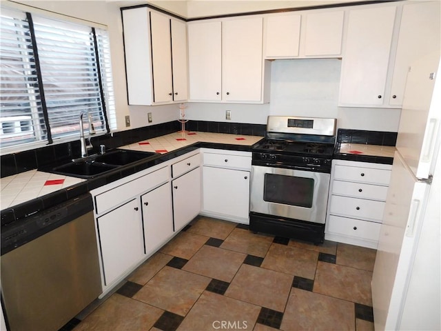 kitchen featuring appliances with stainless steel finishes, tile countertops, sink, and white cabinets