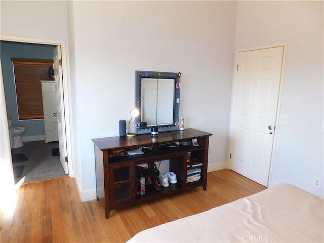 bedroom with connected bathroom and hardwood / wood-style floors