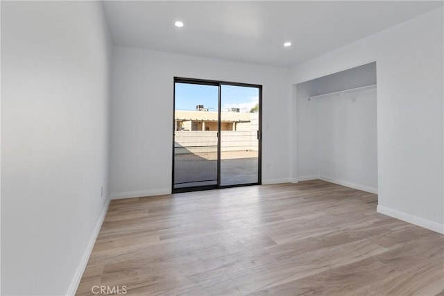 unfurnished bedroom featuring access to outside, a closet, and light wood-type flooring