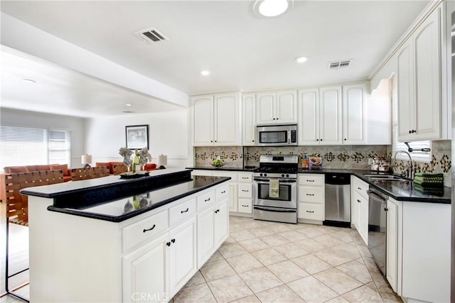 kitchen featuring sink, appliances with stainless steel finishes, a center island, tasteful backsplash, and white cabinets