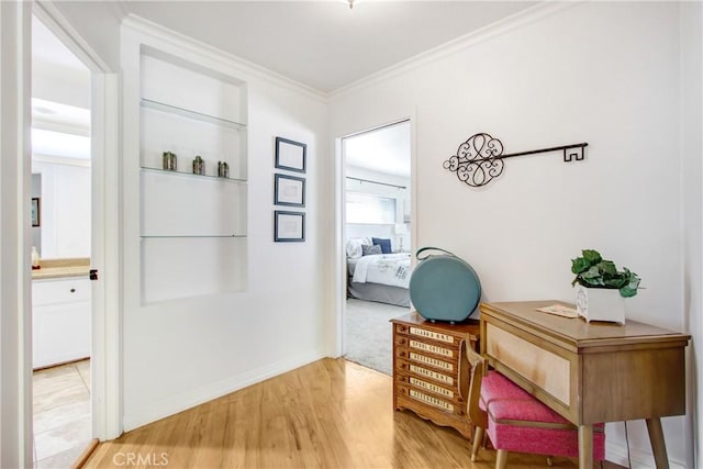 home office featuring built in shelves, wood-type flooring, and ornamental molding