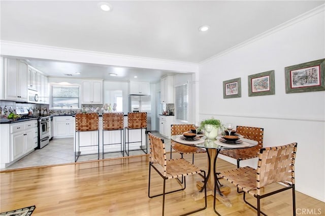 dining space with crown molding and light wood-type flooring