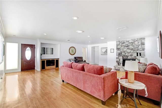 living room with a stone fireplace and light hardwood / wood-style floors