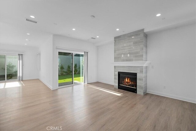 unfurnished living room with a wealth of natural light, a high end fireplace, and light hardwood / wood-style flooring