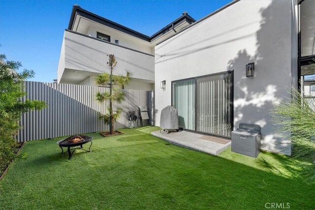 back of property featuring a yard and an outdoor fire pit