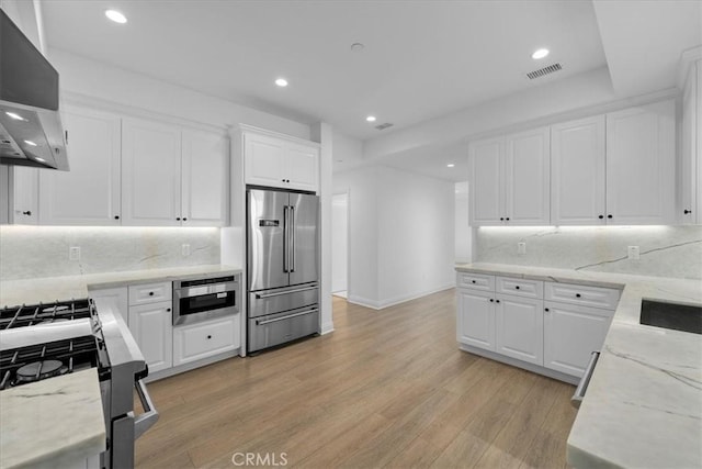 kitchen featuring stainless steel appliances, light stone counters, light hardwood / wood-style floors, white cabinets, and exhaust hood