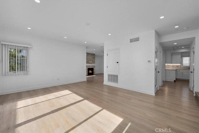 unfurnished living room featuring wood-type flooring and a large fireplace