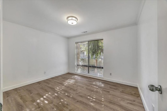 empty room with crown molding and hardwood / wood-style floors