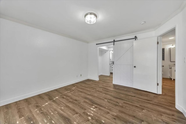 unfurnished bedroom with crown molding, a barn door, and dark wood-type flooring