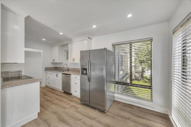 kitchen with light wood-type flooring, appliances with stainless steel finishes, sink, and white cabinets