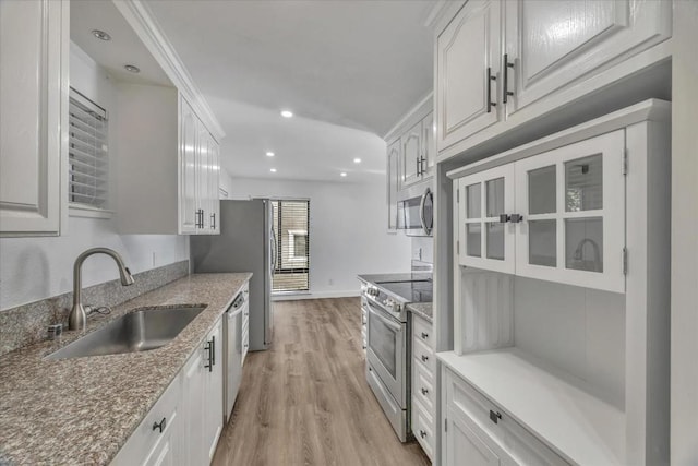 kitchen featuring sink, light hardwood / wood-style flooring, white cabinetry, stainless steel appliances, and light stone countertops