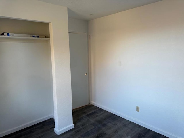 unfurnished bedroom with dark hardwood / wood-style flooring and a closet