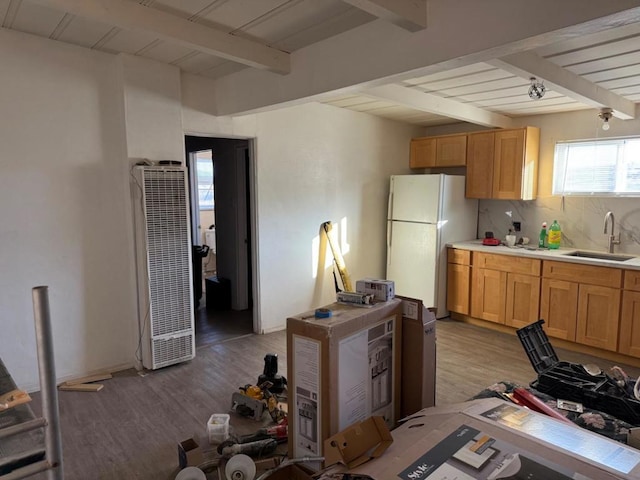 kitchen with sink, white refrigerator, tasteful backsplash, beamed ceiling, and light wood-type flooring