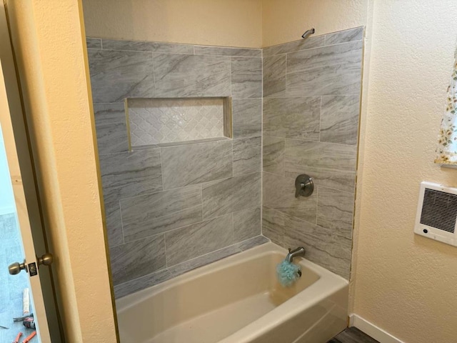 bathroom featuring tiled shower / bath combo and heating unit