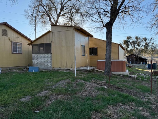 view of home's exterior with a yard, a hot tub, and a sunroom