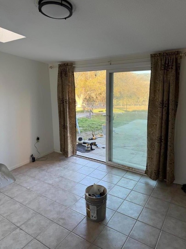 empty room with plenty of natural light, a skylight, and light tile patterned floors