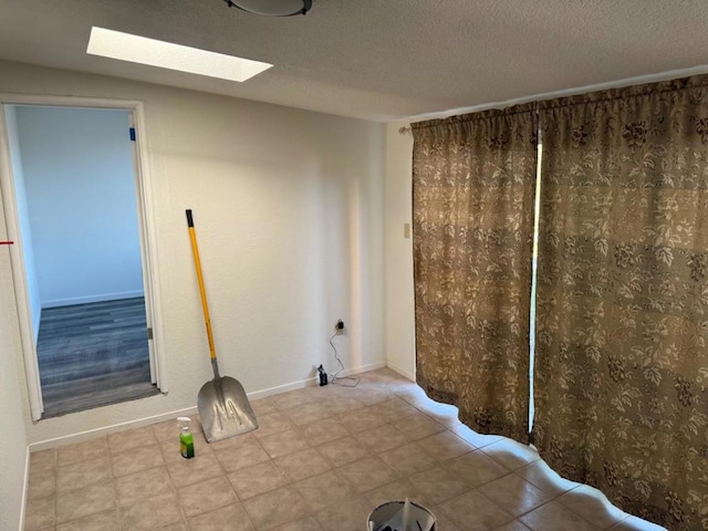 unfurnished room with a skylight and a textured ceiling