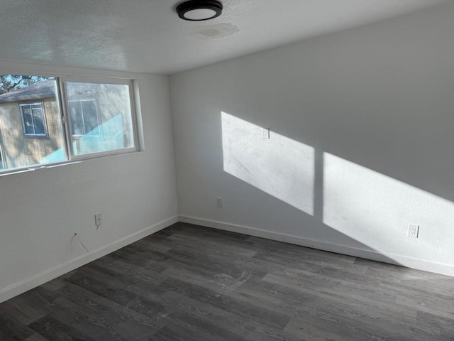 spare room with dark hardwood / wood-style flooring and a textured ceiling