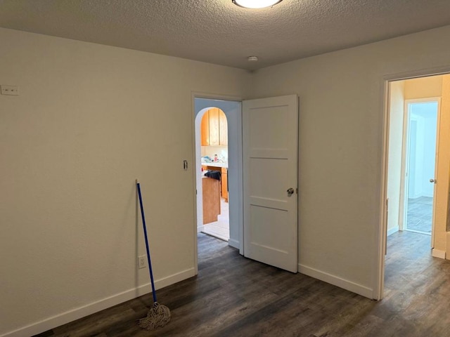 unfurnished room with dark wood-type flooring and a textured ceiling