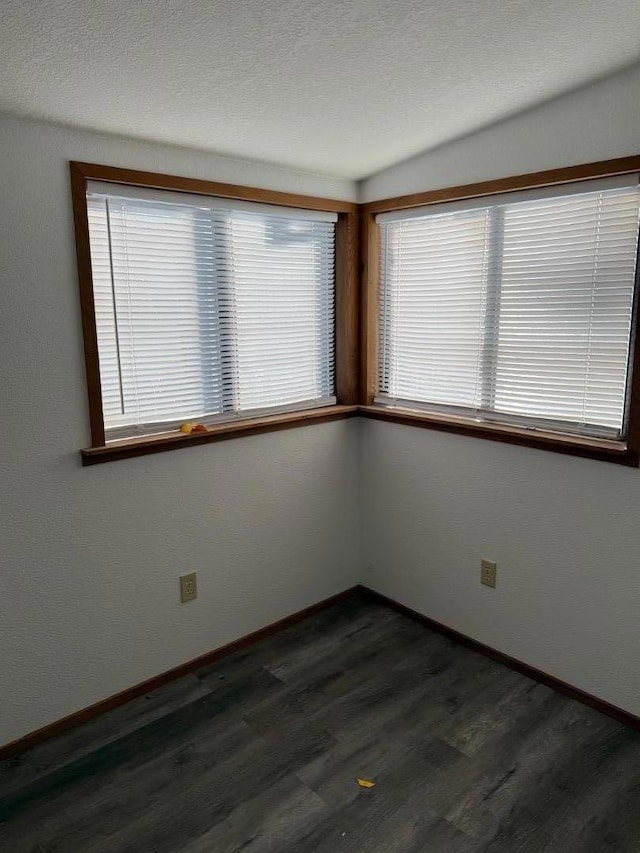 spare room featuring dark hardwood / wood-style floors and a textured ceiling