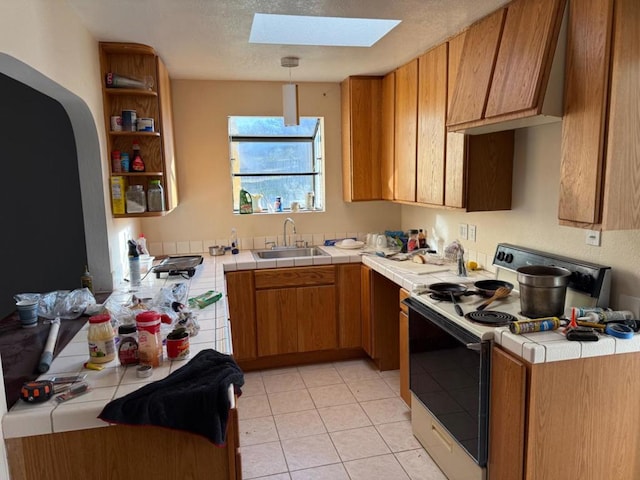 kitchen with pendant lighting, sink, a skylight, white range with electric stovetop, and tile counters