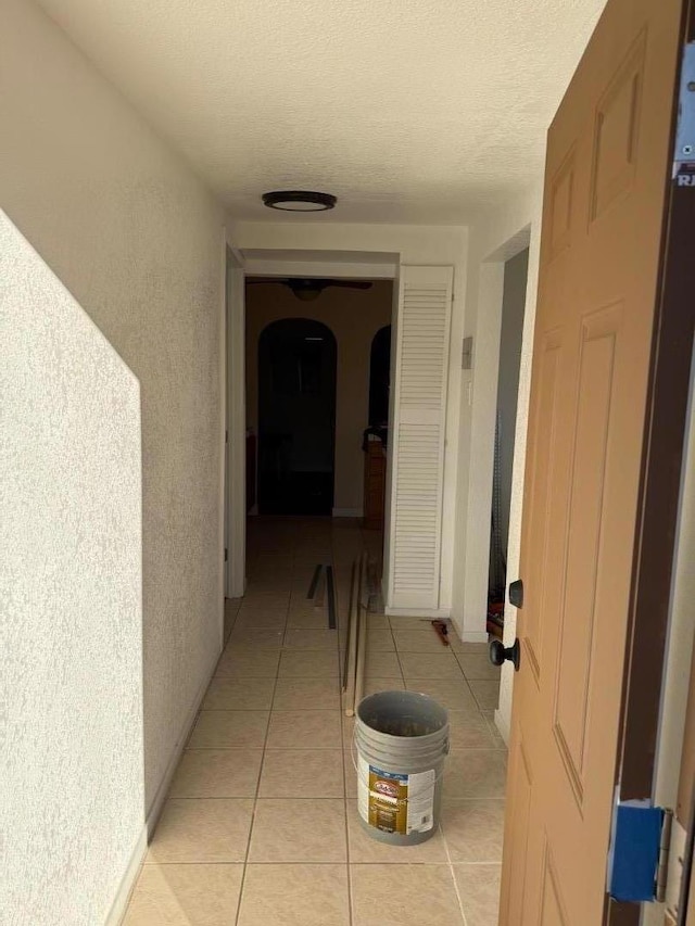 hallway featuring light tile patterned flooring and a textured ceiling