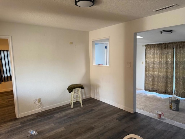 spare room featuring dark hardwood / wood-style floors and a textured ceiling