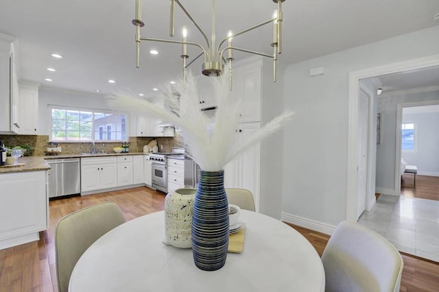 dining room with sink, light hardwood / wood-style flooring, and ornamental molding