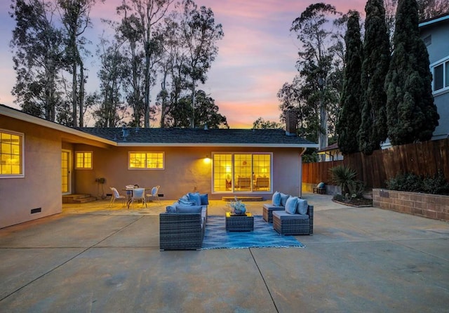 back house at dusk featuring a patio and an outdoor hangout area