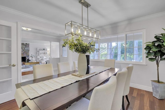 dining space featuring a fireplace, ornamental molding, and dark hardwood / wood-style floors