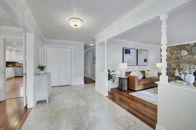 entryway featuring decorative columns, crown molding, and light hardwood / wood-style floors