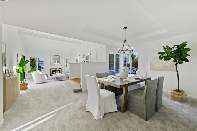 carpeted dining space featuring an inviting chandelier and a tray ceiling