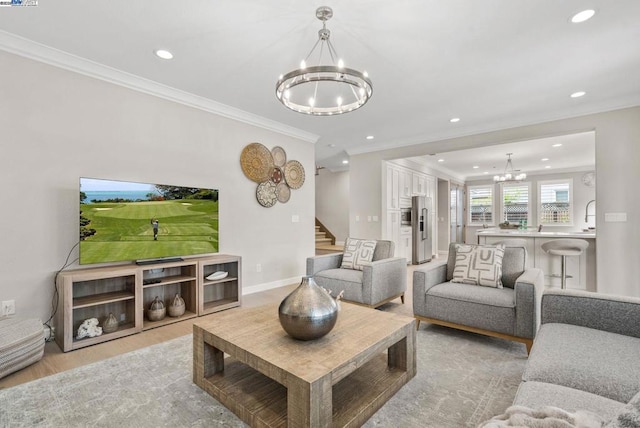 living room with crown molding, light wood-type flooring, and a chandelier