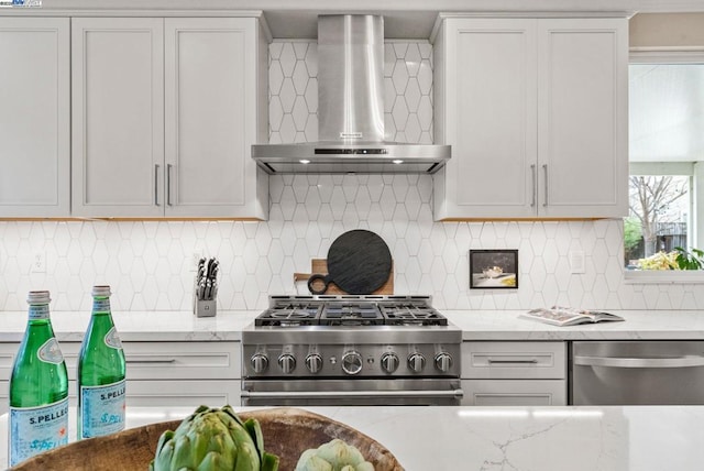 kitchen featuring wall chimney exhaust hood, stainless steel appliances, light stone countertops, and white cabinets