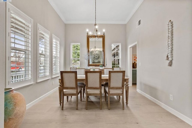 dining area with an inviting chandelier, ornamental molding, and light wood-type flooring