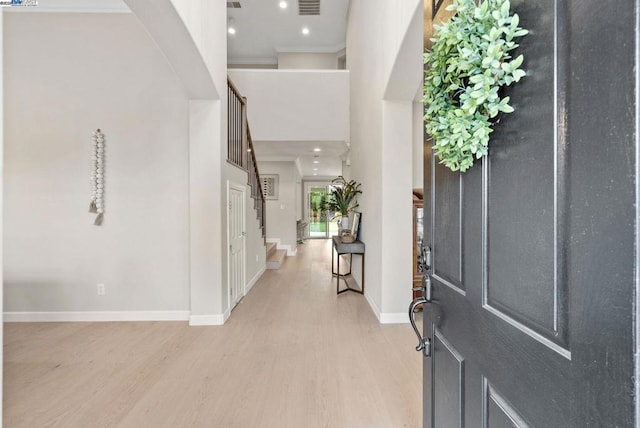 entrance foyer with a towering ceiling and light hardwood / wood-style floors