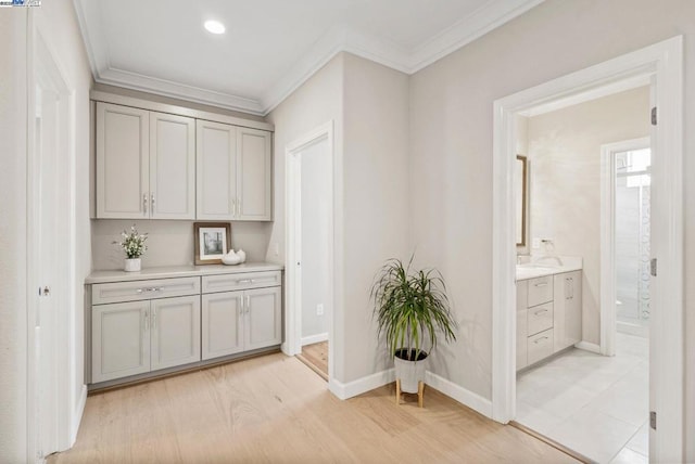 bar with crown molding, light hardwood / wood-style flooring, and gray cabinetry