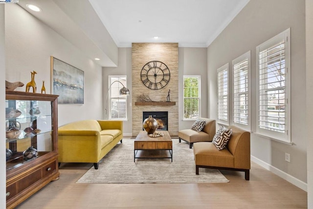 living room featuring a tiled fireplace, hardwood / wood-style floors, and ornamental molding