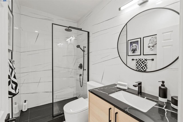 bathroom with tiled shower, vanity, toilet, and tile walls